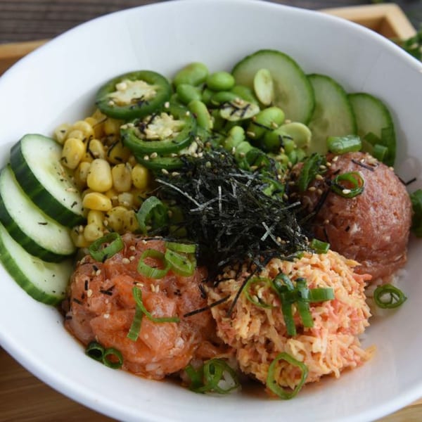 A poke bowl with tuna, salmon, spicy crab, corn, edamame, cucumbers, and jalapeños.