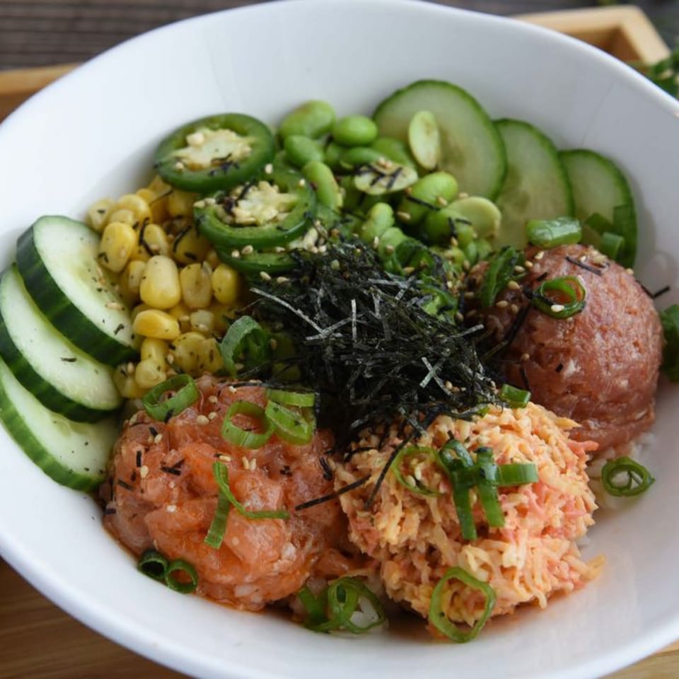 A poke bowl with tuna, salmon, spicy crab, corn, edamame, cucumbers, and jalapeños.